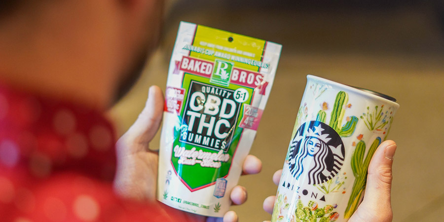 close up view of a person's back while holding a pack of CBD THC gummies with his left hand and a starbucks cup on his right